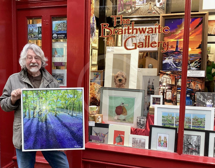 Artist Paul Freeman in front of gallery with one of his bluebell paintings